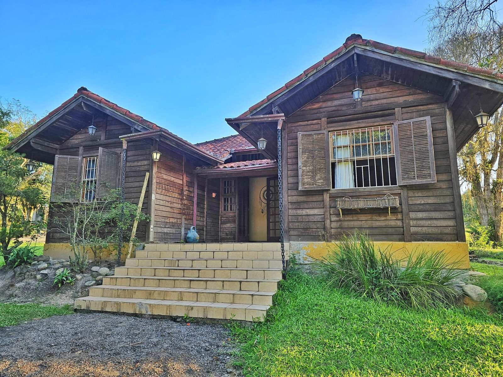 Fachada frontal da casa-filha com escadaria de tijolo, entre o jardim