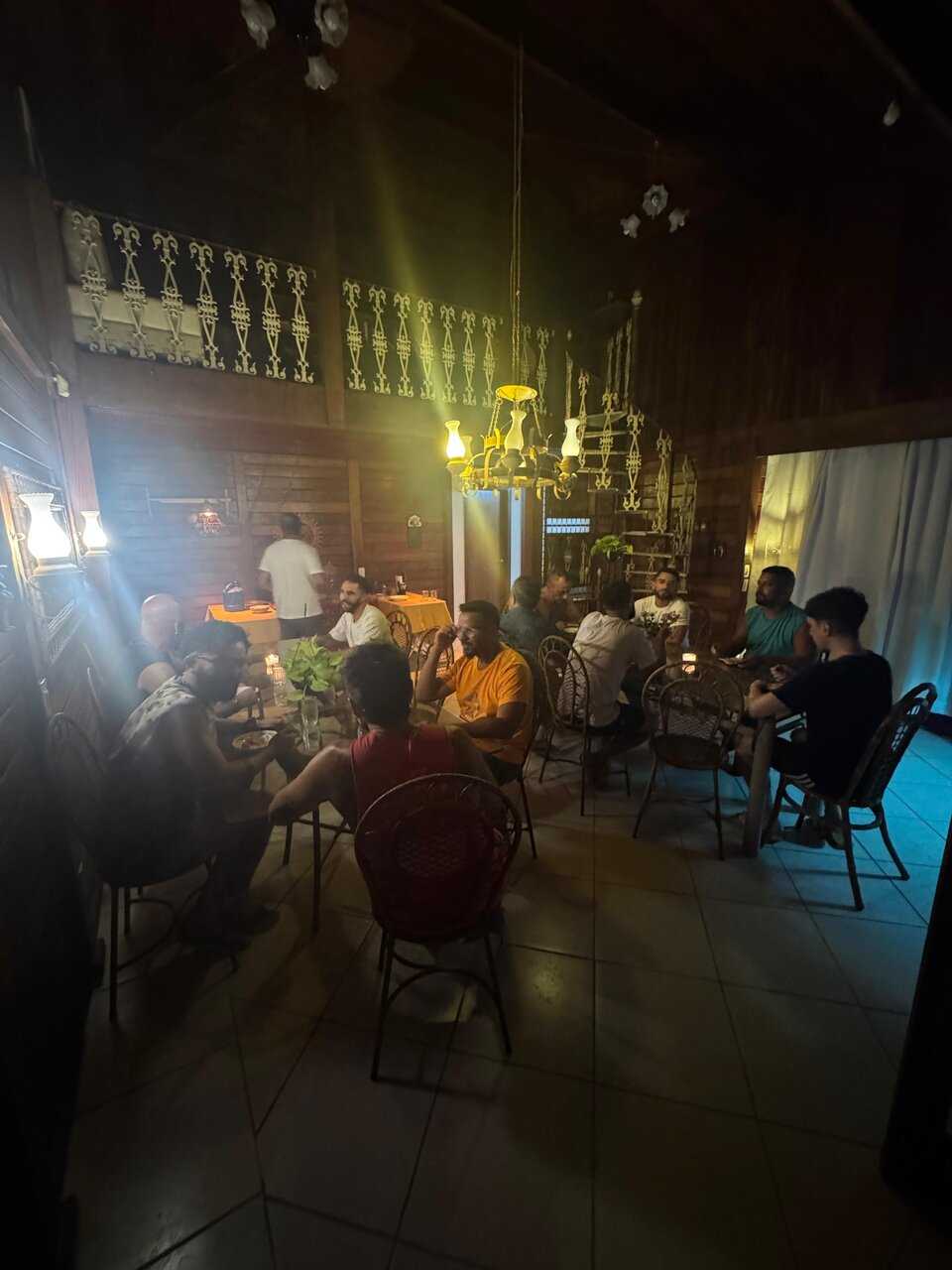 Jantar noturno em grupo sob luzes douradas no refeitório