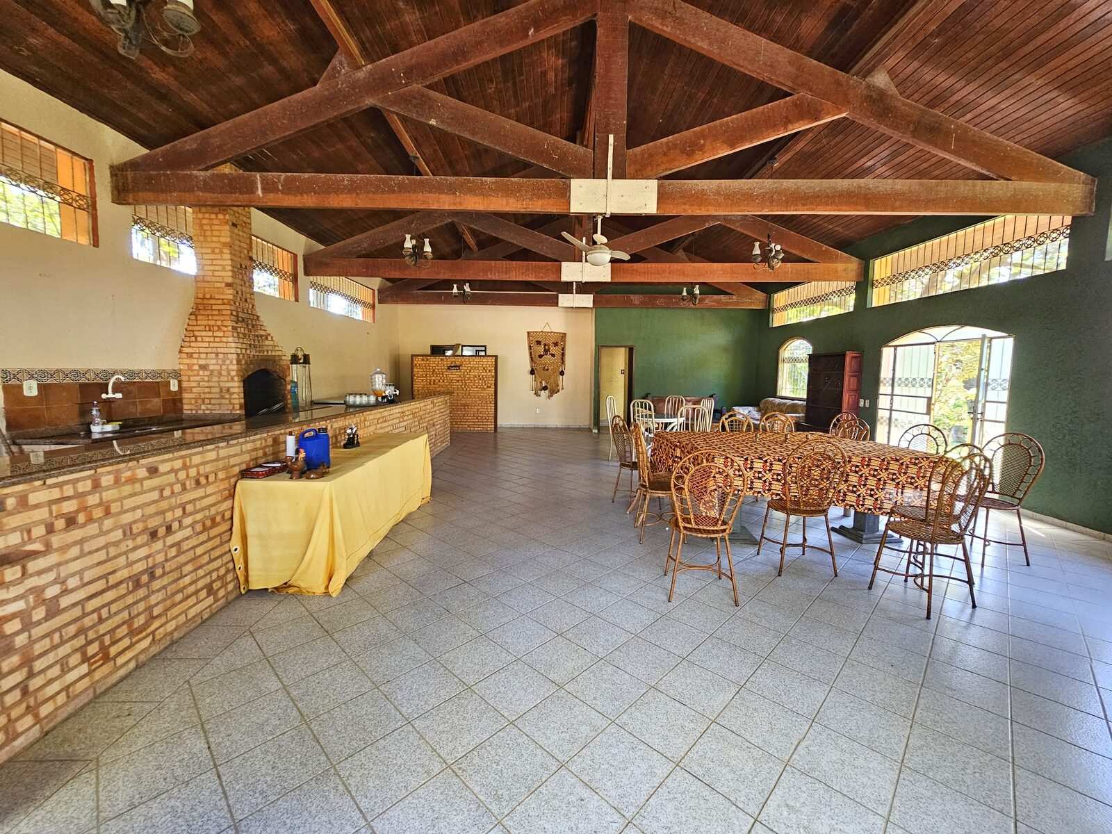 Salão interno do refeitório com churrasqueira de tijolo e mesas de vime